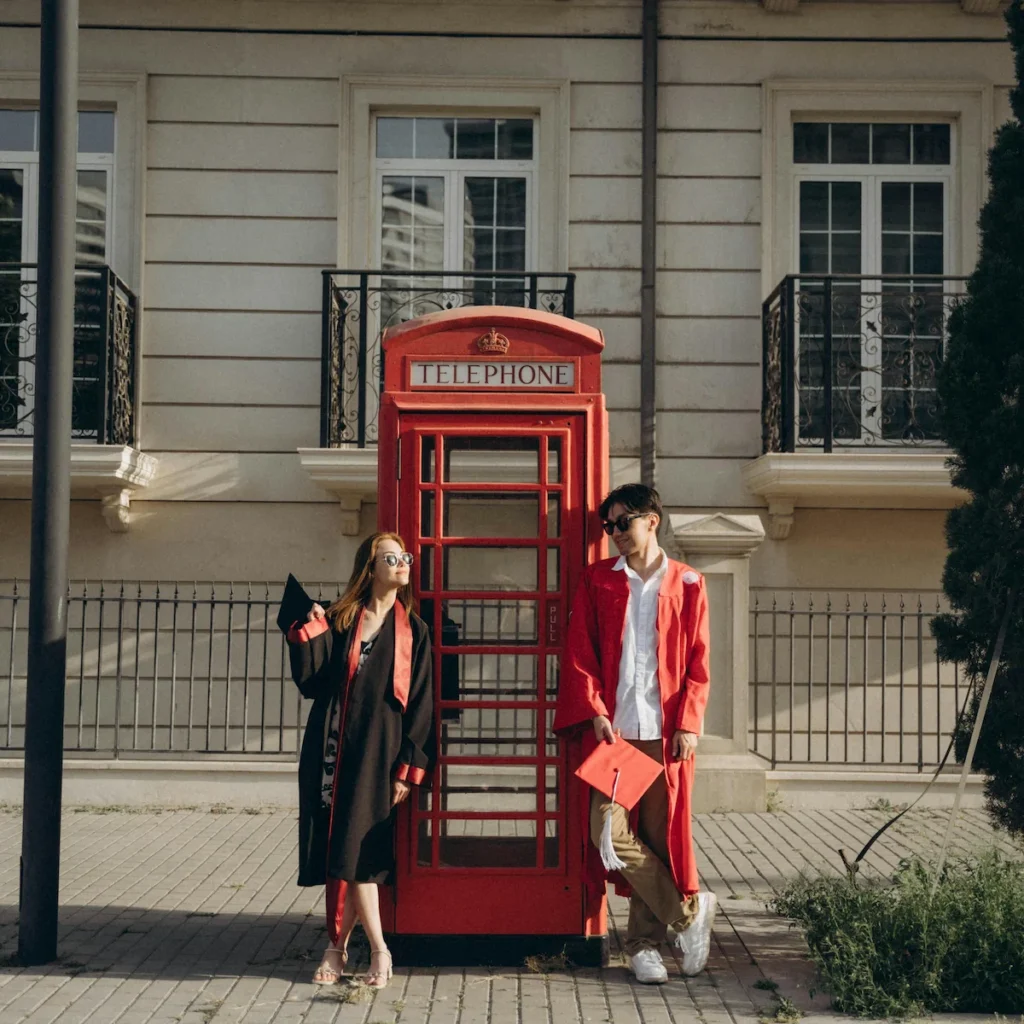 Absolventen posieren in einer Telefonzelle in London