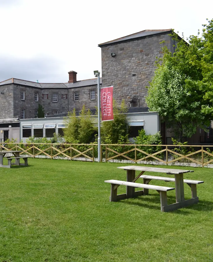 Grüne Rasenfläche mit Sitzgelegenheiten auf dem Campus des Griffith College Dublin.