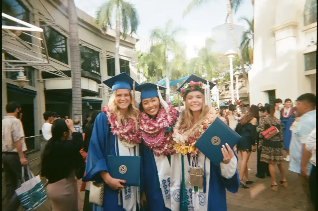 Internationale Studierende feiern ihren Abschluss auf Hawaii in tropischer Umgebung.