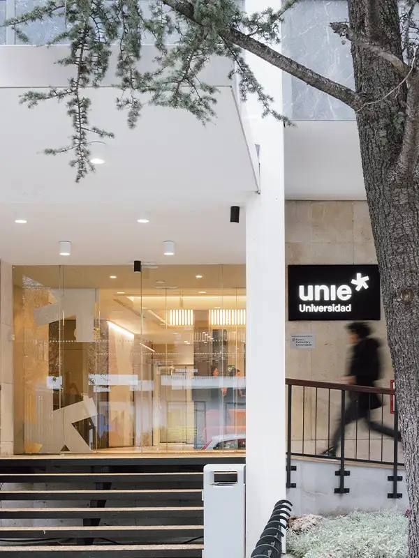 Eingang der UNIE Universidad in Madrid mit moderner Glasfassade und vorbeigehenden Studierenden.