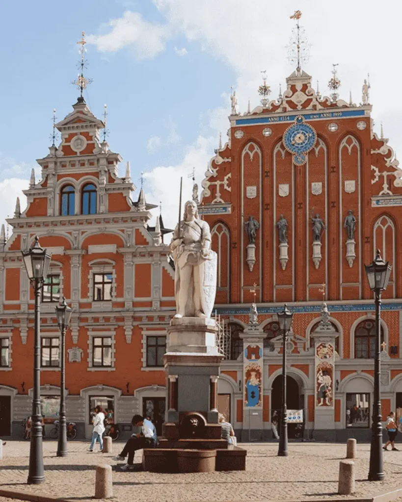 Historisches Schwarzhäupterhaus am Rathausplatz in Riga mit Statue und Passanten im Vordergrund